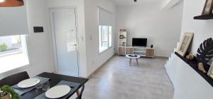 a white living room with a table and a tv at LA MARCELINO in Patagones
