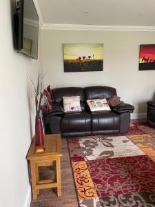 a living room with a leather couch and a table at OAK LODGE in Tillingham