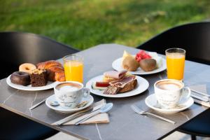 a table with plates of food and cups of orange juice at Leonardo Hotel San Sebastián in Donostia-San Sebastián