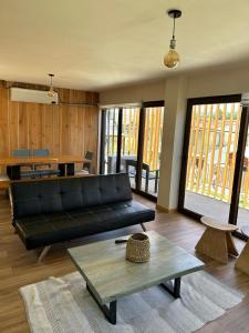 uma sala de estar com um sofá preto e uma mesa em Casa Boqui Hostal em Panguipulli