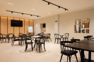 a restaurant with tables and chairs and a flat screen tv at Leonardo Hotel San Sebastián in Donostia-San Sebastián