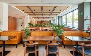 a restaurant with couches and tables and plants at Leonardo Hotel San Sebastián in Donostia-San Sebastián +34 photos