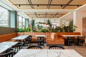 a restaurant with tables and chairs and plants at Leonardo Hotel San Sebastián in Donostia-San Sebastián