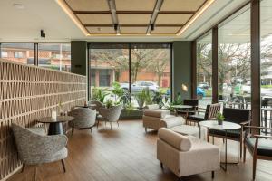 a lobby with tables and chairs and windows at Leonardo Hotel San Sebastián in Donostia-San Sebastián