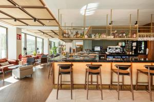 a restaurant with a bar with stools and tables at Leonardo Hotel San Sebastián in Donostia-San Sebastián