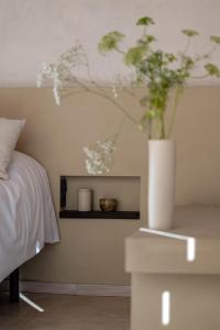 a white vase with flowers on a table next to a bed at Cabañas Agotzenea in Zubiri