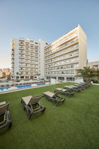 een rij chaise loungestoelen op een gazon voor een gebouw bij Sandos Griego in Torremolinos