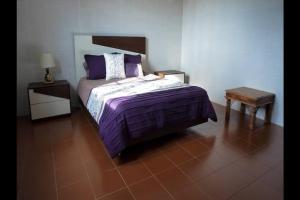 a bedroom with a bed with purple sheets and a table at Vila Nova in Vila Franca do Campo