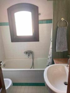 a bathroom with a tub and a sink and a window at PortoCervo Cala Del Faro in Arzachena