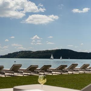 a row of chairs sitting next to a body of water at LUA Resort - Adults only in Balatonfüred