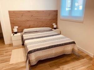 1 dormitorio con 1 cama con cabecero de madera en LURGORRI APARTAMENTOS by Gernihost, en Guernica y Luno