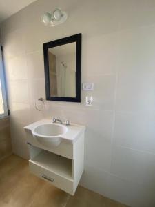 La salle de bains blanche est pourvue d'un lavabo et d'un miroir. dans l'établissement Sea view las grutas, à Las Grutas