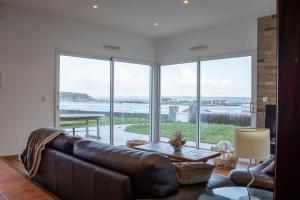 a living room with a leather couch and large windows at Ti Ma Zud/Vue mer/Wifi in Camaret-sur-Mer