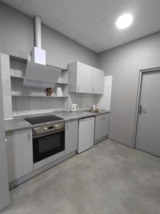 a kitchen with white cabinets and a stove top oven at Hostel PLUNKSA in Marijampolė