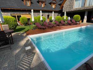 a swimming pool with lounge chairs next to a building at Hotel Koliba in Senec