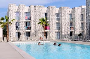 un groupe de personnes dans une piscine en face d'un bâtiment dans l'établissement Résidence Prestige Odalys Nakâra, au Cap d'Agde
