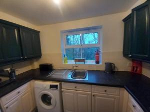 a kitchen with a sink and a washing machine at Peaceful Retreat in Basildon - Relocators & Contractors Welcome in Great Burstead