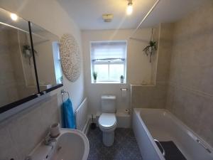 y baño con aseo, bañera y lavamanos. en Peaceful Retreat in Basildon - Relocators & Contractors Welcome en Great Burstead