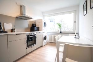 cocina con electrodomésticos blancos, mesa y ventana en Juno - #1 Terrassen-Apartment, Netflix, WLAN, en Bottrop