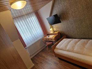 a small room with a bed and a desk with a television at Gasthof Hosbein in Heiligenberg
