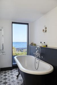 a bath tub in a bathroom with a large window at Stunning architect designed beachfront property in Selsey