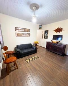 - un salon avec un canapé noir et une télévision dans l'établissement Casa Dende Corumbau 5 Min Praia de Corumbau, à Barra de Itabapoana