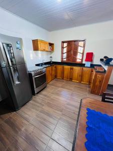 La cuisine est équipée d'un réfrigérateur en acier inoxydable et de placards en bois. dans l'établissement Casa Dende Corumbau 5 Min Praia de Corumbau, à Barra de Itabapoana