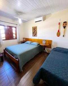1 dormitorio con 2 camas, mesa y ventana en Casa Dende Corumbau 5 Min Praia de Corumbau en Barra de Itabapoana