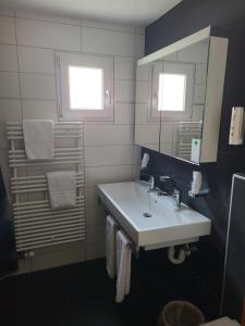 een badkamer met een witte wastafel en een spiegel bij Hotel Residence in Grindelwald