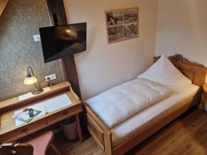 a small bedroom with a bed and a desk at Gasthof Hosbein in Heiligenberg