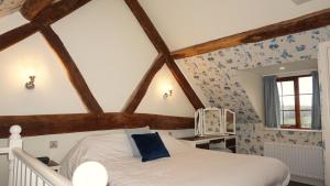 a bedroom with a white bed with blue wallpaper at Wheat Cottage - 5* Cyfie Farm with private covered hot tub in Llanfyllin