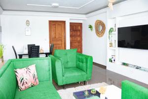 uma sala de estar com cadeiras verdes e uma televisão em appartement cosy moon bonapriso em Douala