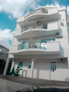 a white building with balconies and a motorcycle parked in front at Apartmani SAMB Igalo in Herceg-Novi