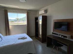 sypialnia z łóżkiem, telewizorem i biurkiem w obiekcie Condomínio Kaimã w mieście Matinhos