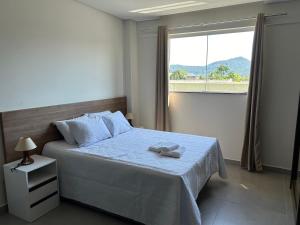 a bedroom with a bed and a large window at Condomínio Kaimã in Matinhos