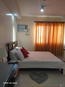 a bedroom with a large bed with red pillows at Persimmon Studio Single Unit in Cebu City