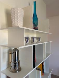une étagère blanche avec des livres et un vase sur elle dans l'établissement Appartamento Du Lac, à Baveno