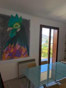 une table en verre dans une pièce ornée d'une peinture de coq dans l'établissement Appartamento Du Lac, à Baveno