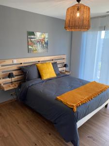 a bedroom with a bed with a blue comforter and yellow pillows at CHAMBRES D'HOTES Chez Nicole et Christian in Villaz