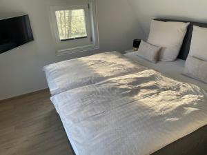 Cette chambre comprend un grand lit blanc et une fenêtre. dans l'établissement Haus am Teich, à Worpswede