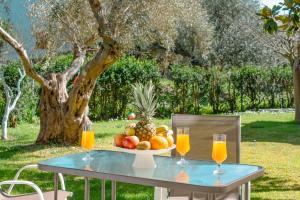 una mesa con un bol de fruta y dos vasos de zumo de naranja en Olia Apartments S, en Ligia
