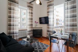 ein Wohnzimmer mit einem Tisch und einem TV in der Unterkunft Teatro Ariston & Piazza Colombo Elegant Apartment in Sanremo