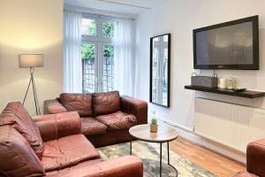 a living room with leather furniture and a flat screen tv at Homely 4-bedroom House in Manchester