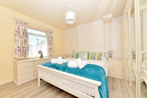 Schlafzimmer mit einem Bett mit blauer Bettwäsche und einem Fenster in der Unterkunft Pembroke Villa in Shanklin