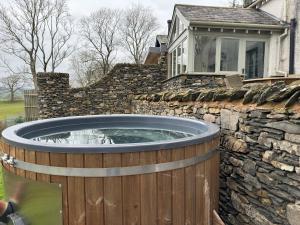 a hot tub in a stone wall next to a house at Dove Tail Barn in Underbarrow