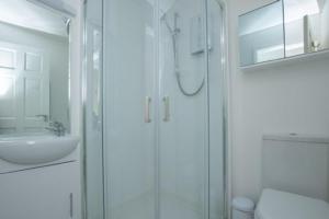 een witte badkamer met douche en wastafel bij Chalet Thirtyone in Deal +14 foto's