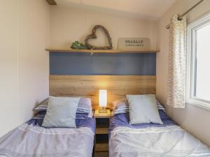 two beds in a small room with a window at Seasalt in West Mersea