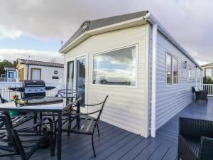 a tiny house with a table and chairs on a deck at Seasalt in West Mersea