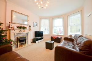 uma sala de estar com um sofá de couro e uma árvore de Natal em St Georges Villa em Ryde