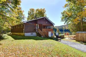 a small house with a large yard next to a lake at Waterfront - Chalet des Becassines in Nominingue